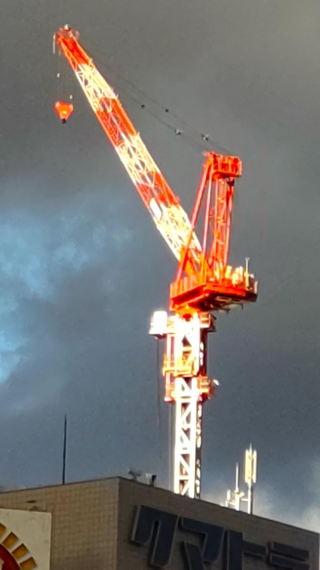  A heavy craftsman standing in the sky: a male figure of a tower crane