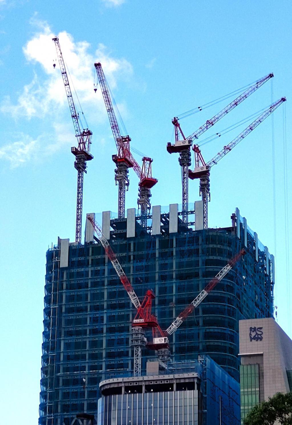  A heavy craftsman standing in the sky: a male figure of a tower crane